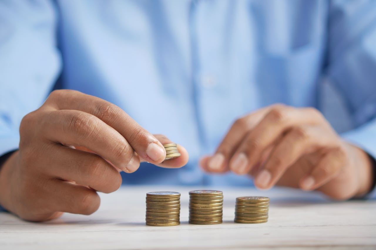 Services-03 Close-up of hands stacking gold coins, symbolizing financial growth and savings.